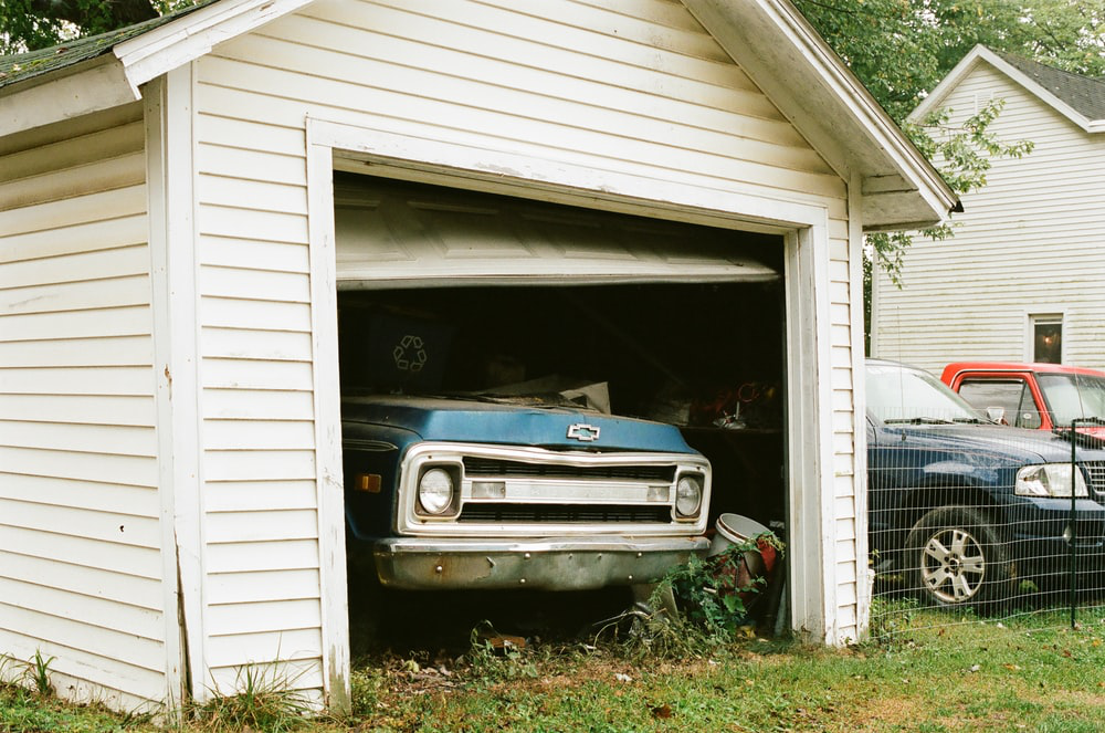 A car parked in a garage with a broken door